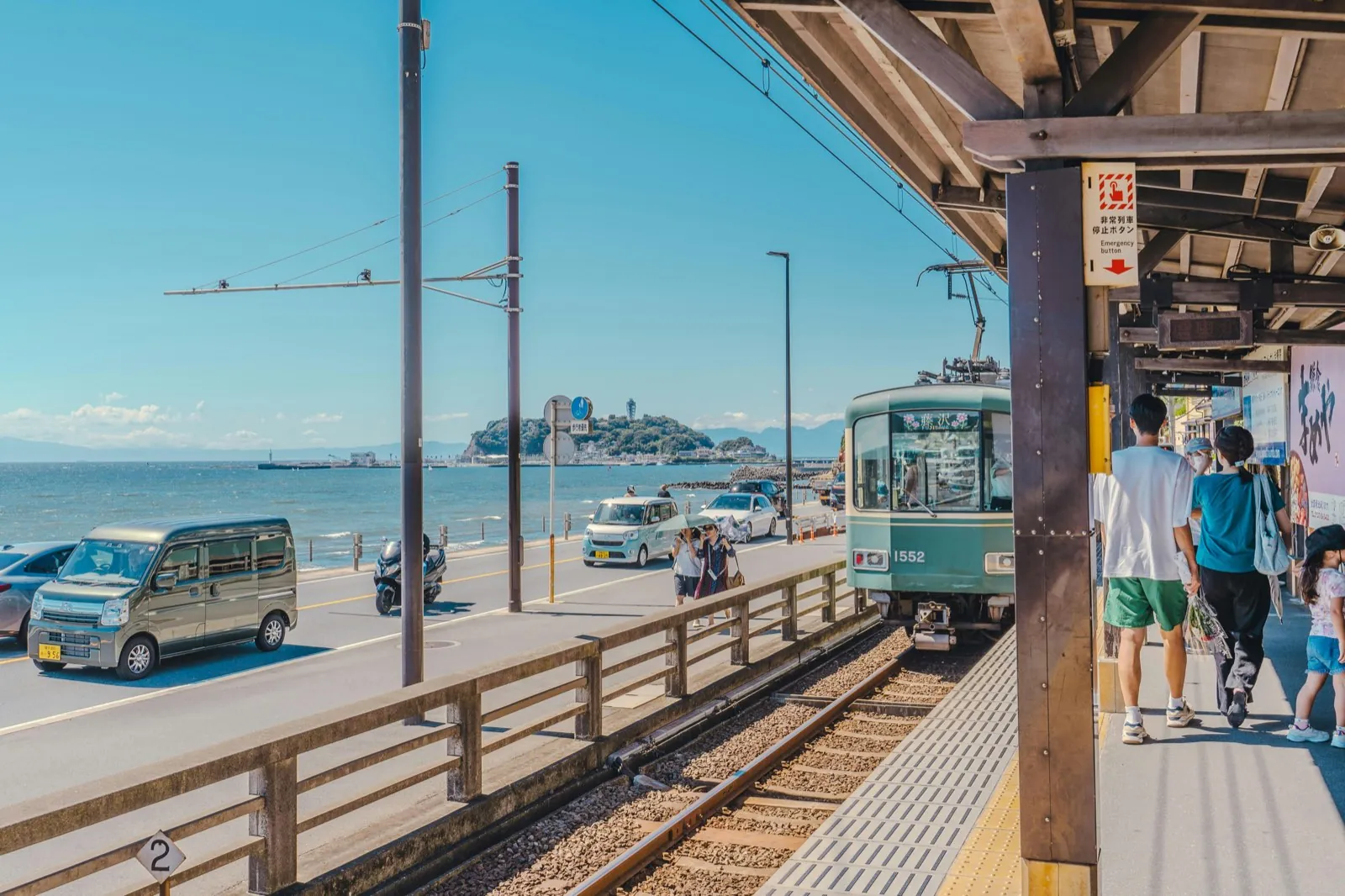 Enoden-trein langs de kust met het eiland Enoshima op de achtergrond in Kamakura