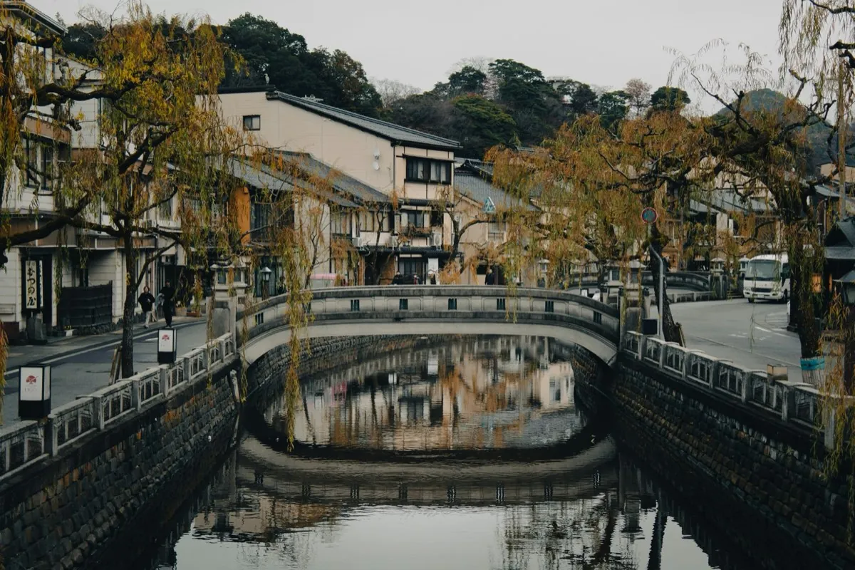 Kanaal van Kinosaki met een stenen brug en wilgen weerspiegeld in het water
