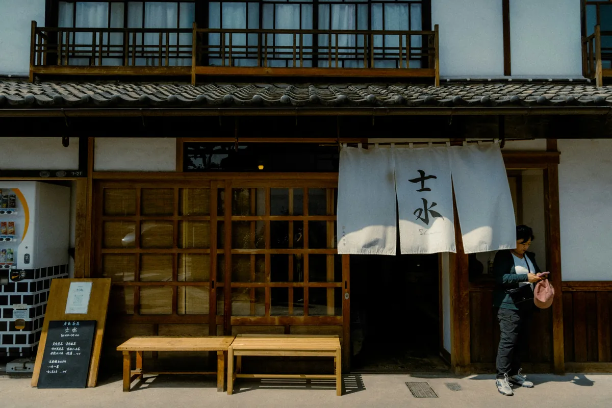 Traditionele houten gevel en witte muur met een opgehangen noren, in een straat van de Bikan-wijk van Kurashiki
