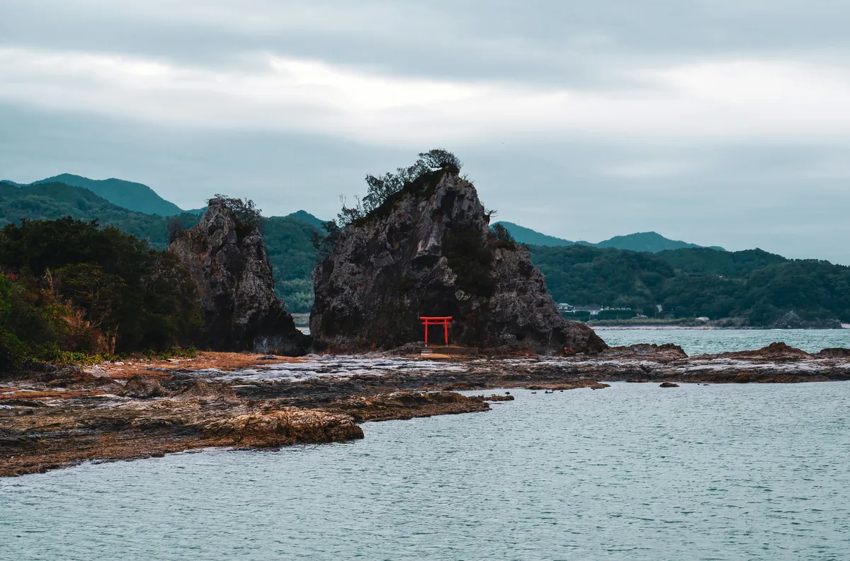 Kleine rode torii tussen rotsformaties aan zee aan de kust van Wakayama
